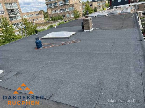Bitumen dakbedekking op plat dak met lichtkoepel en schoorsteen in Rucphen